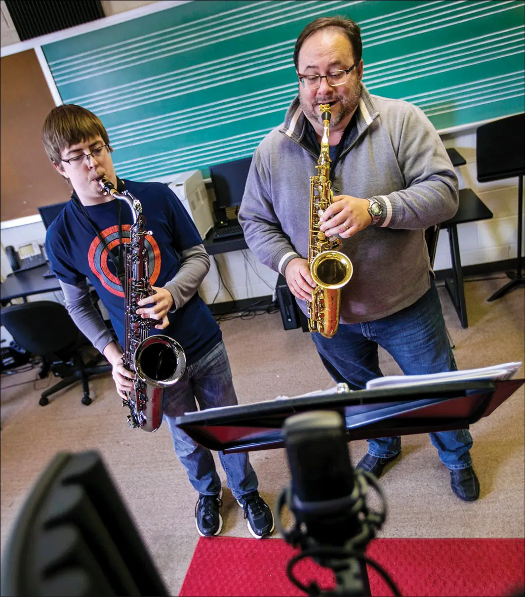 Teacher and student playing saxophone and looking at music stand