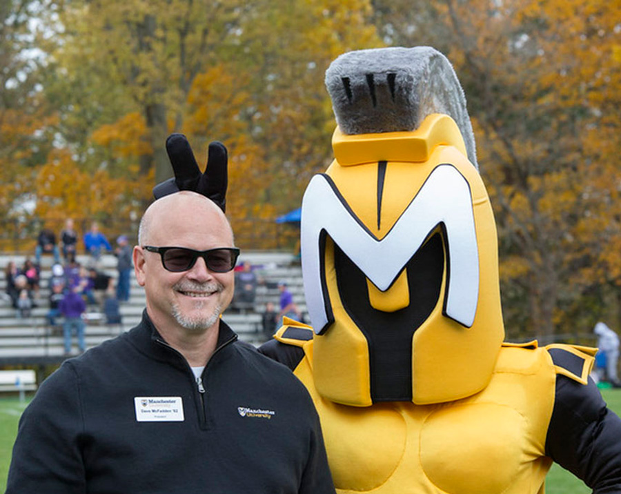 Manchester University Spartan mascot giving the bunny ears to Dave McFadden