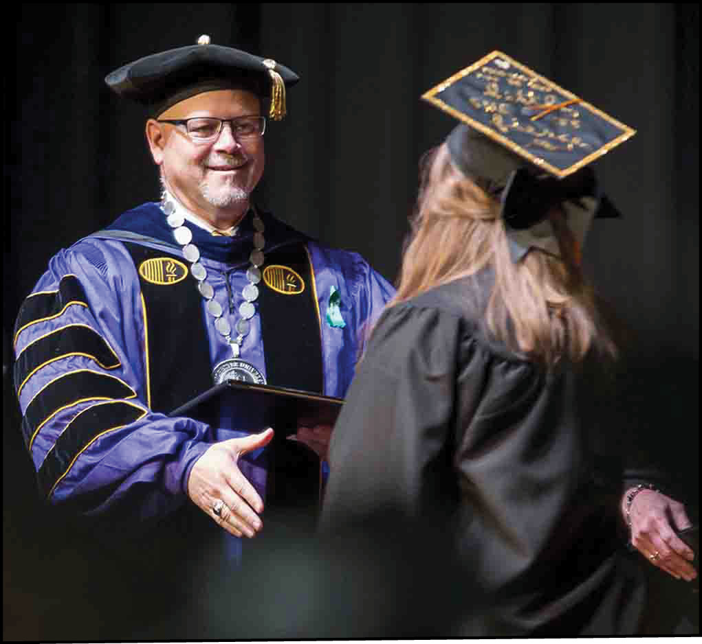 President McFadden in mid embrace of graduate