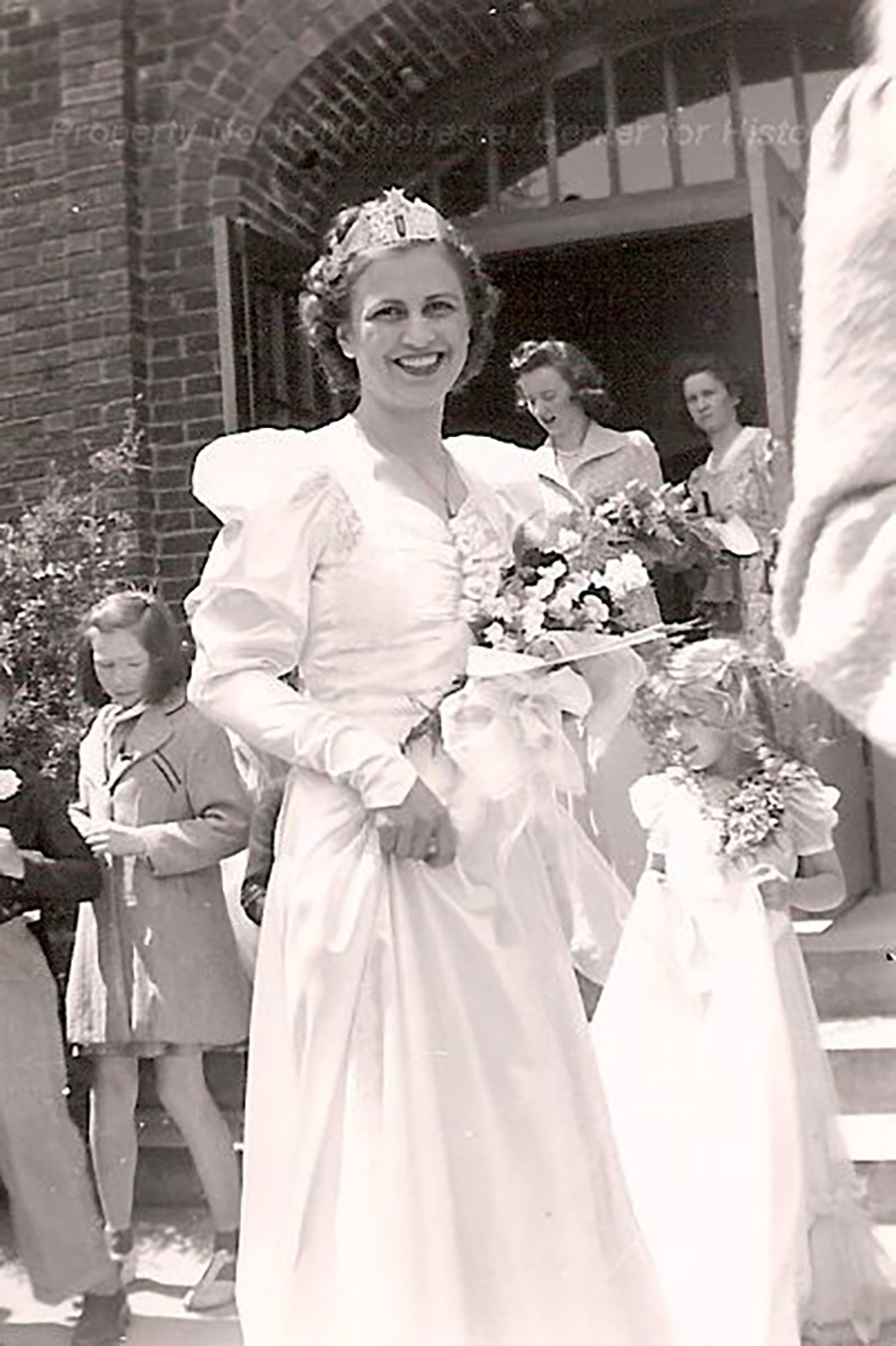 Black and white photo of Evelyn in a white dress holding flowers