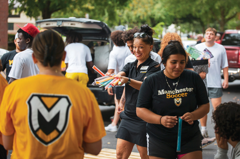 Dr. Stacy H. Young smiling as she hands out snacks at move-in day with other students and people nearby